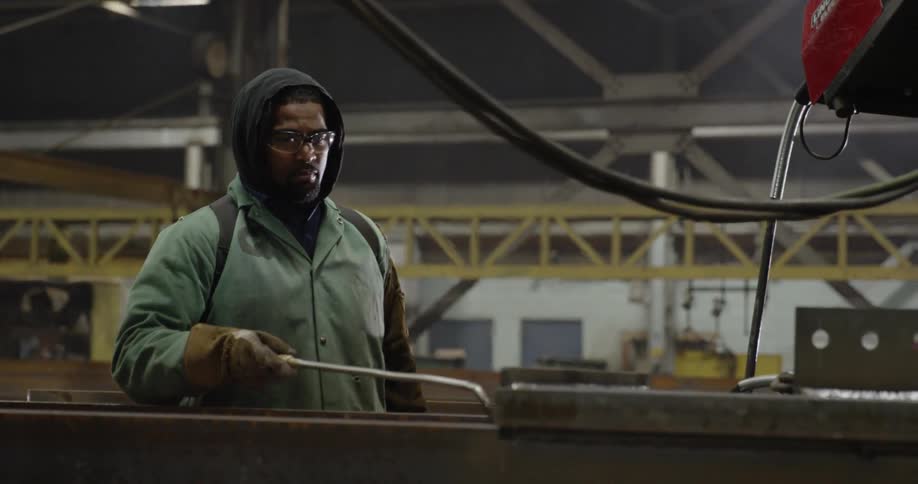 A man is using a torch as he is working in a factory during the day