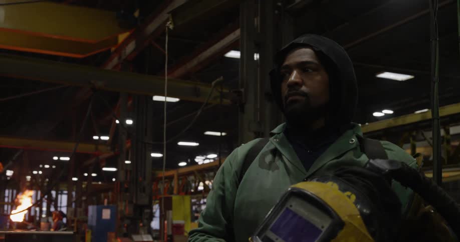 A welder removes his mask in a factory