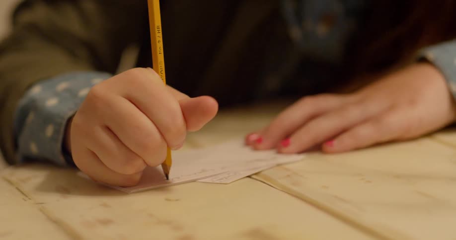 A young girl writes on an index card