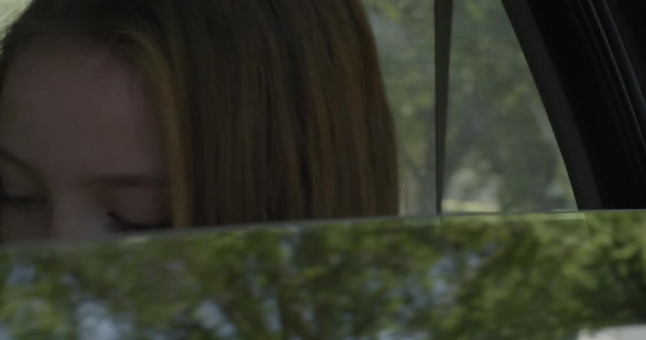 A girl is looking down inside the moving car