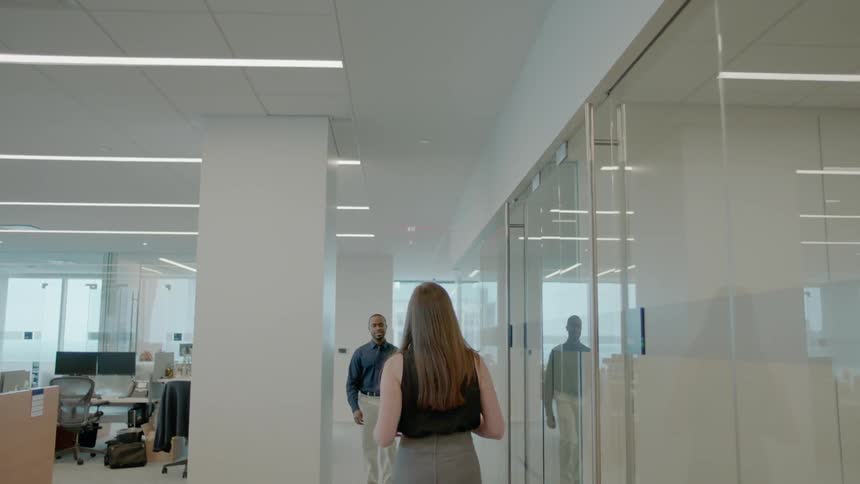 A woman is walking through an office building