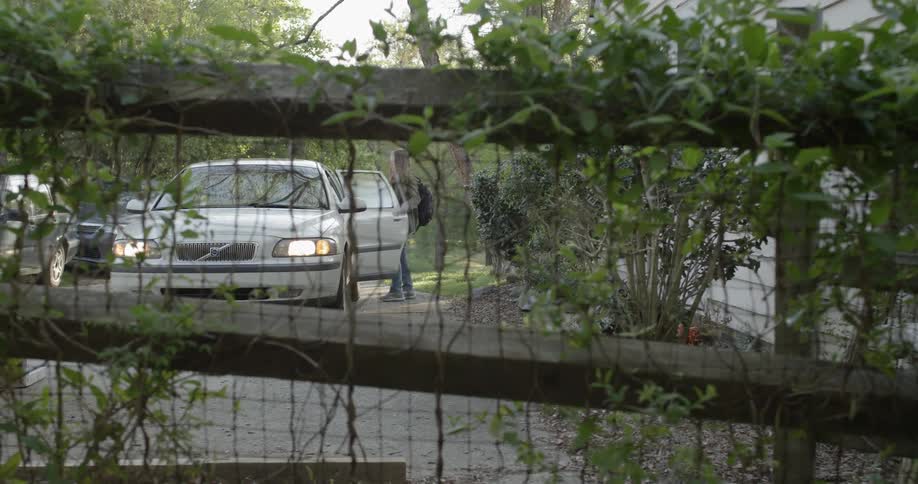 A white car is flashing the headlights as a girl gets in the backseat