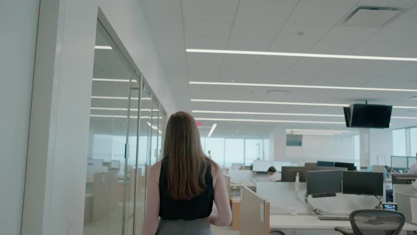 Woman walks past office workstations