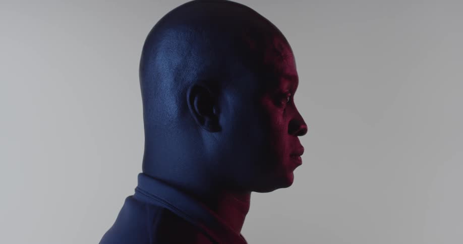 A man stands in the dark with a small light on his face