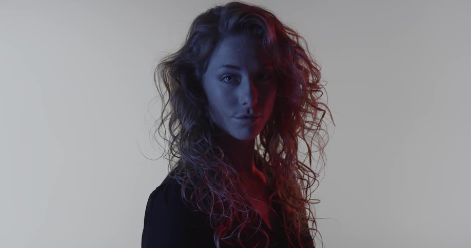 A woman with curly hair turns her head in the dark