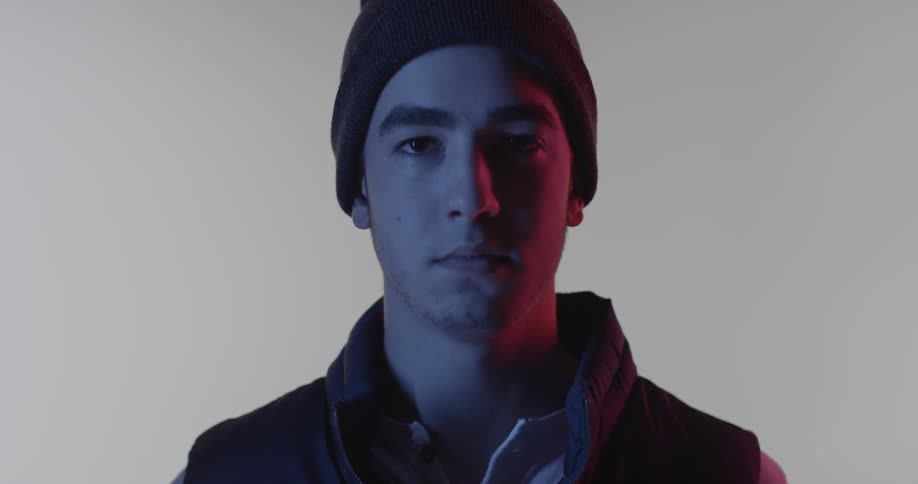 A young man stares forward in a dim room
