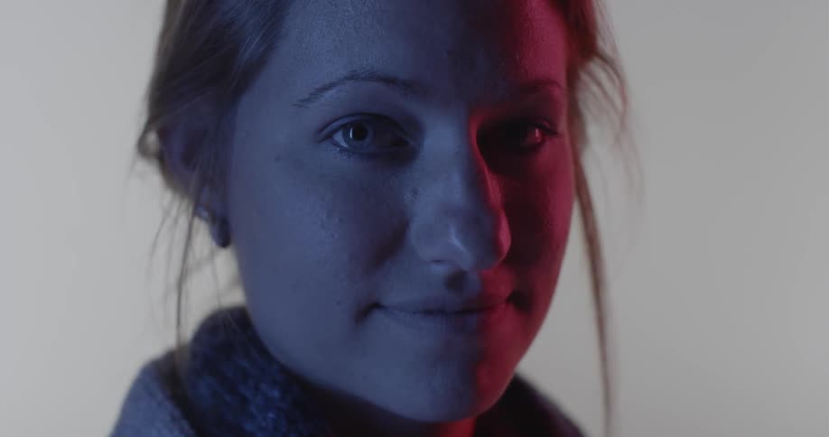 A red lights shines on a woman's face while she stares forward