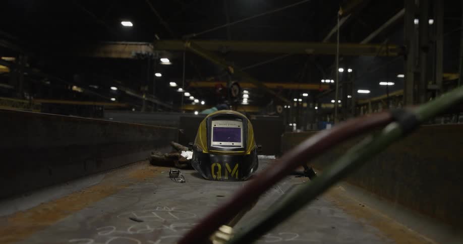 A welding mask sits on top of a steel beam