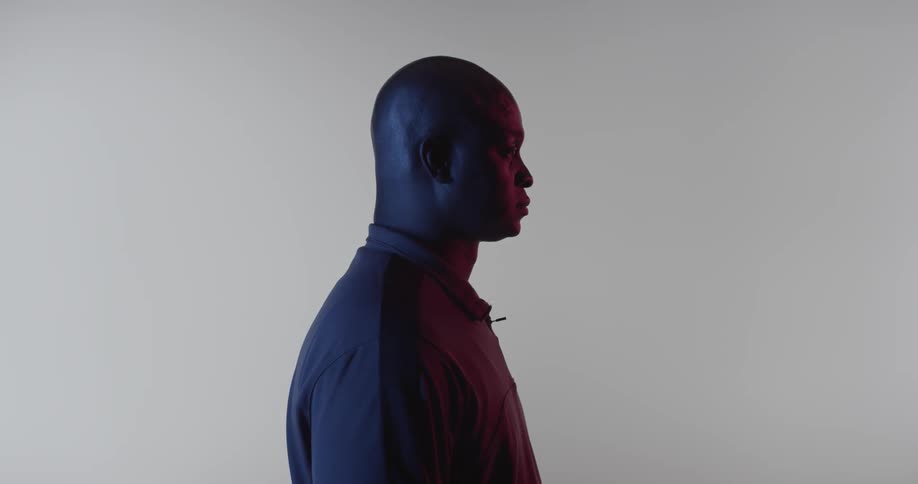 A man with a shaved head stands still