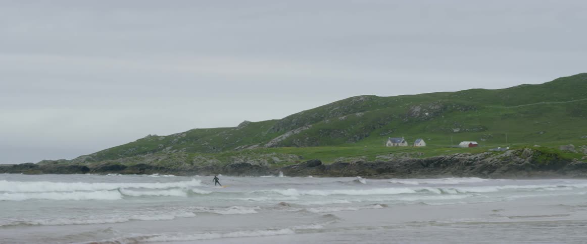 A person is surfing in the water by the shore