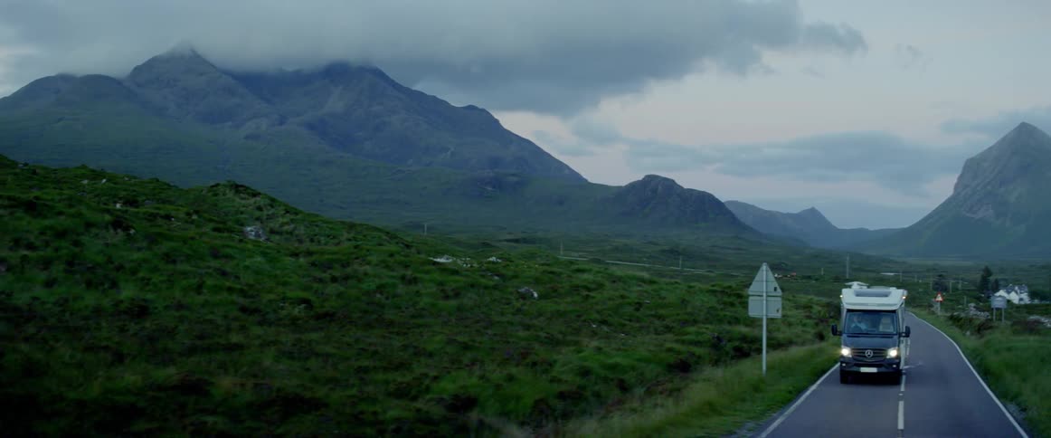 Dark clouds hang over mountain peaks near a road