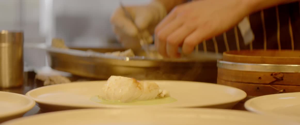 A chef is preparing plates of food in a restaurant