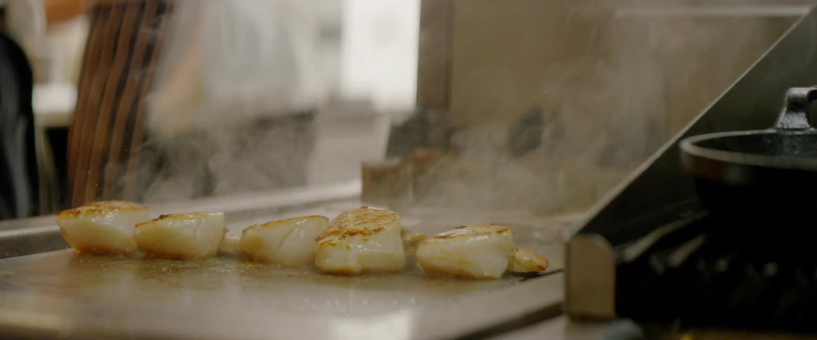 Scallops are cooked and seasoned on a griddle