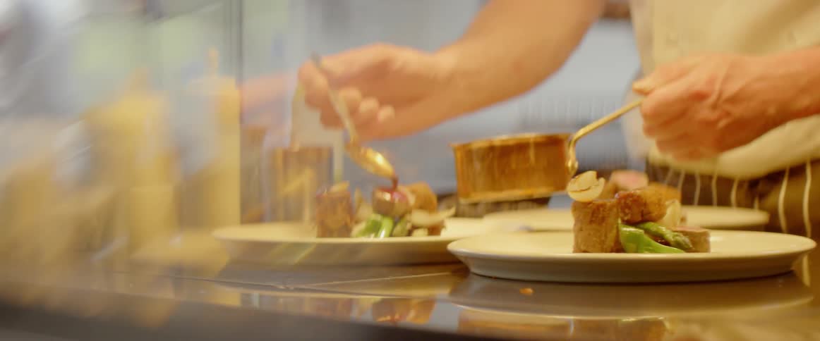 A chef plates food in the kitchen