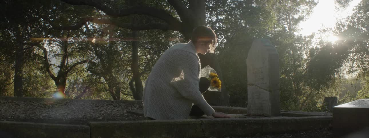 Woman sets flowers in front of a gravestone