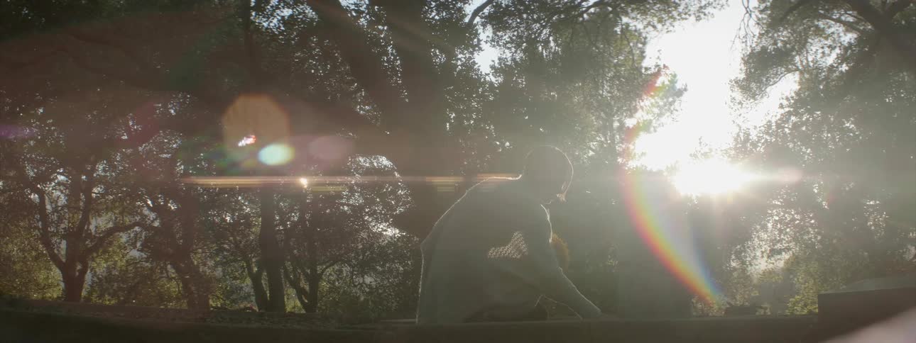 A woman is placing flowers at a gravestone during the day