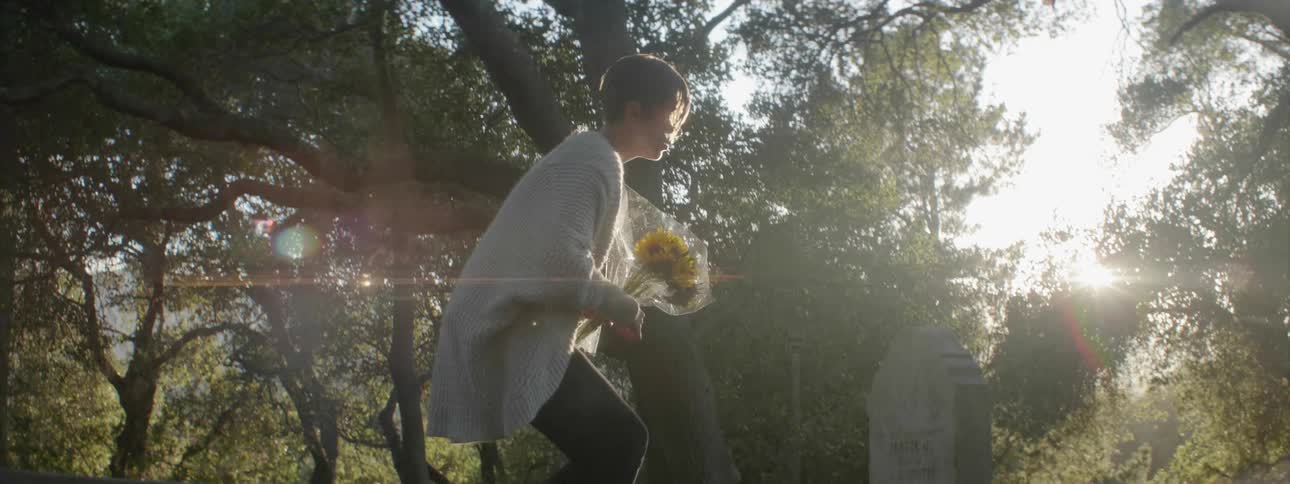 A woman cleans off and then places flowers on a grave