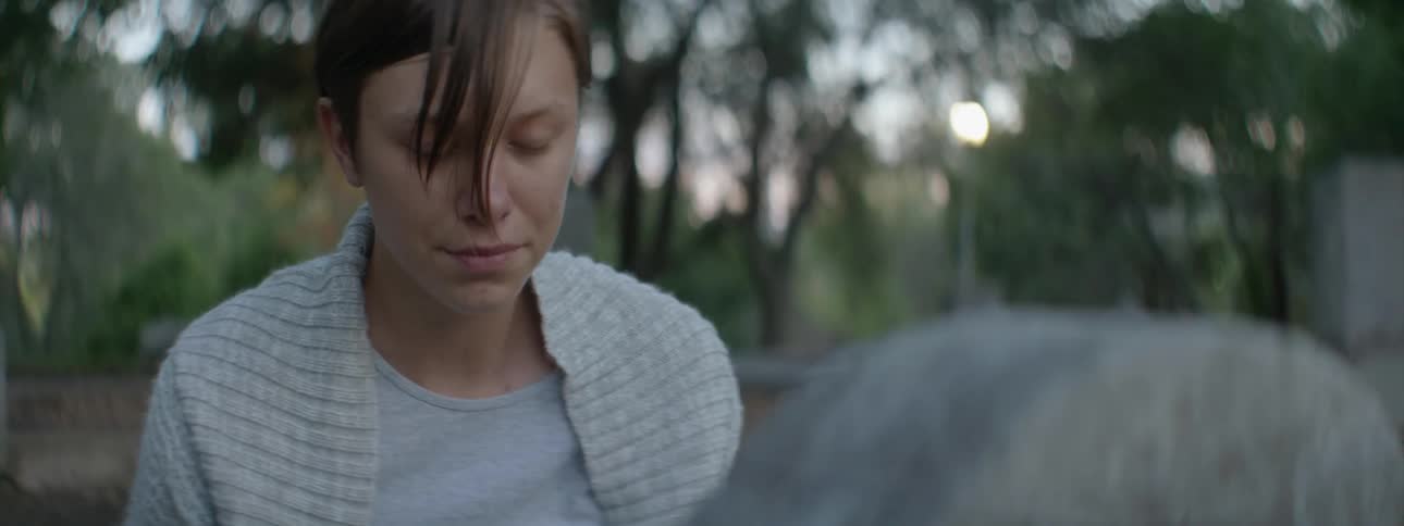 Woman puts a necklace on a gravestone and walks away
