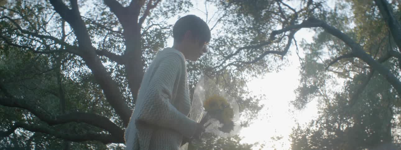 A woman kneels down and places flowers on a grave