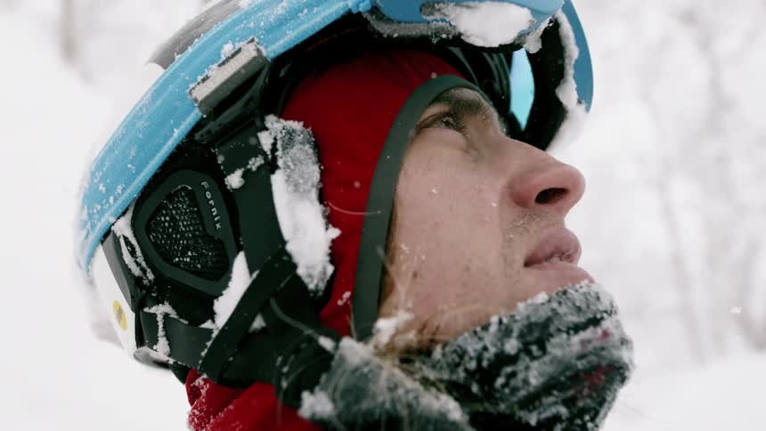 A skier stares up as it snows