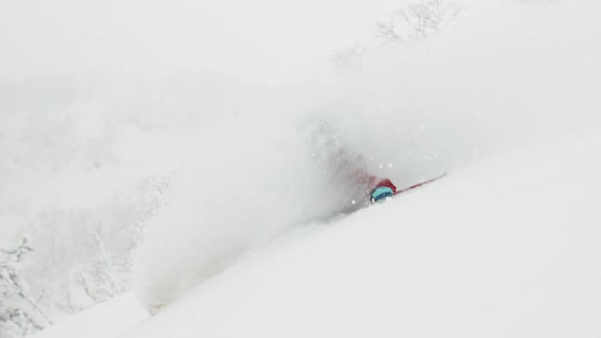 Person skiing a hill as snow kicks up all around