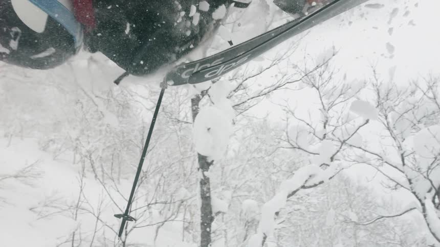 A skier is doing a backflip as he skis on a snowy day