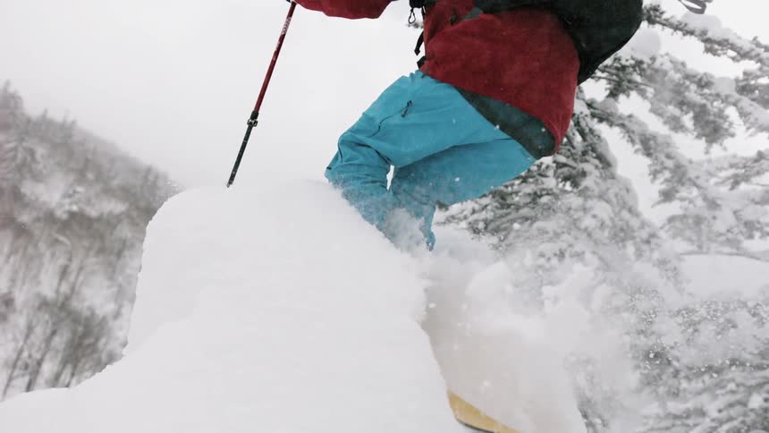 Skier jumping into a tall mound of snow on a cloudy day