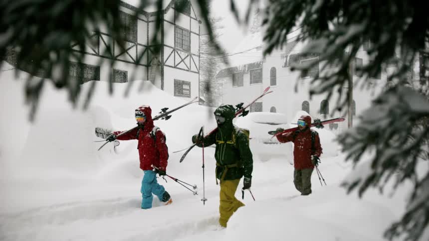 Skiers walk near resort buildings