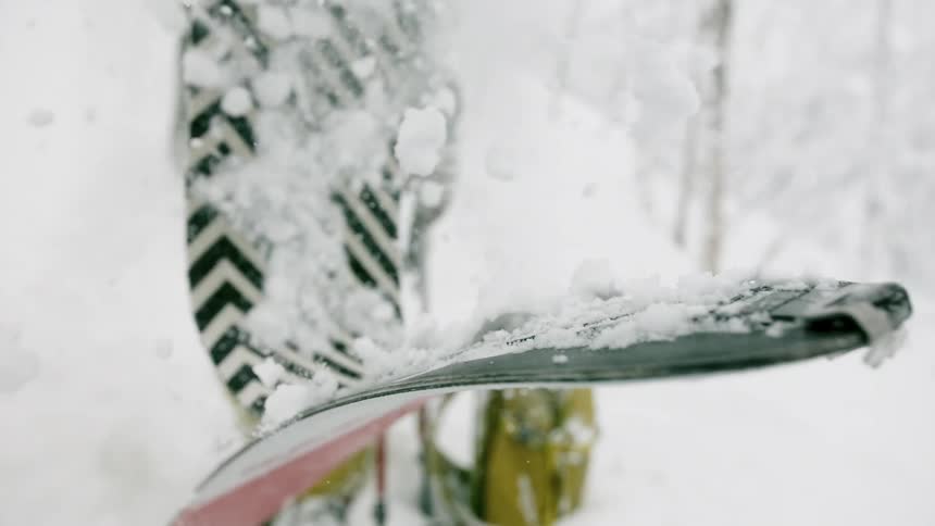 A skier removing a climbing skin from a ski outside in winter