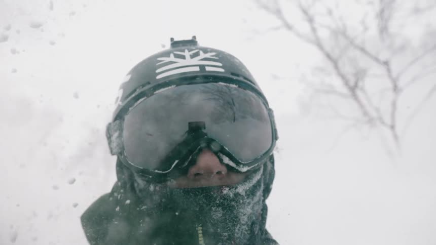 Snow flies around a skier's face in slow motion