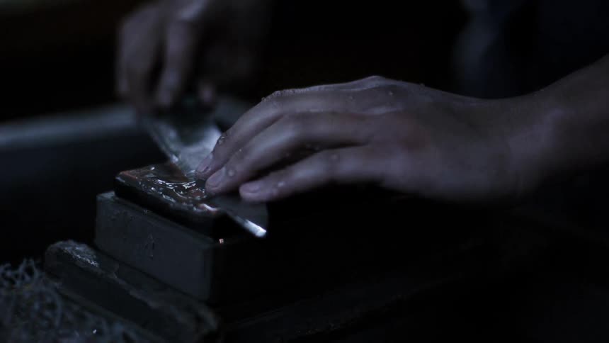 A man sharpens a knife in extreme slow motion