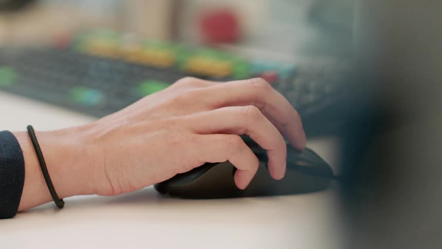 Someone is using a keyboard and mouse and the keyboard has multi colored keys