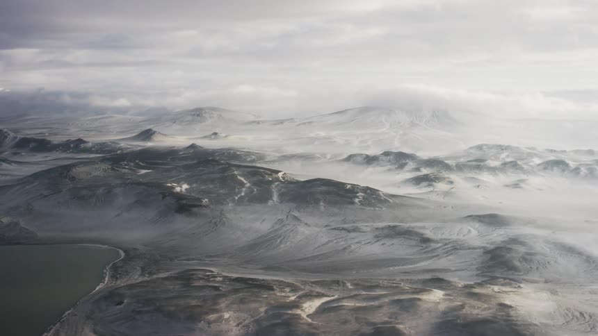 Aerial view of snow covered mountains on a cloudy day
