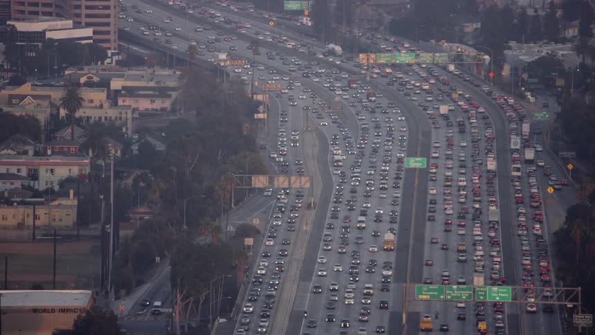 Traffic is flowing on a freeway system in an urban area at dusk