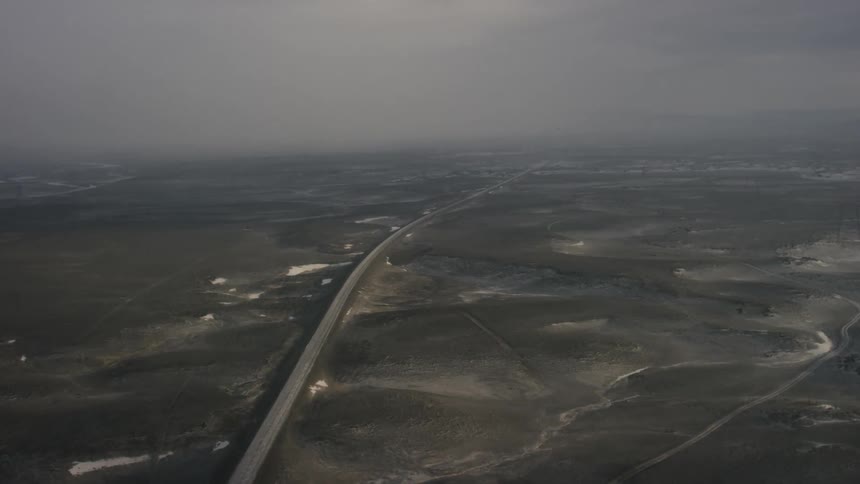 A long road stretches off to a town in the distance