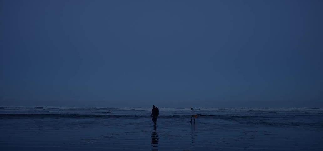 Two people walk on the beach shore