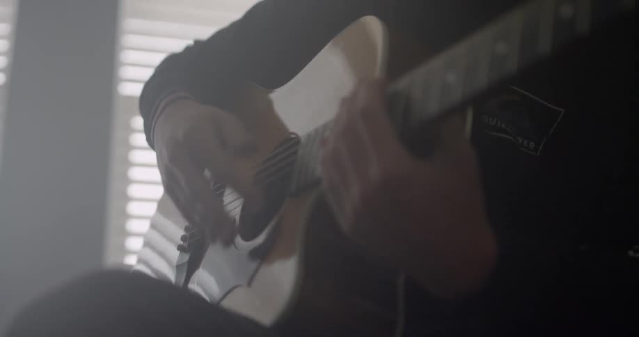 Person playing a guitar indoors in the daytime