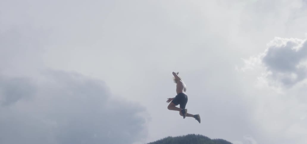 A man swings off of a cliff into the water