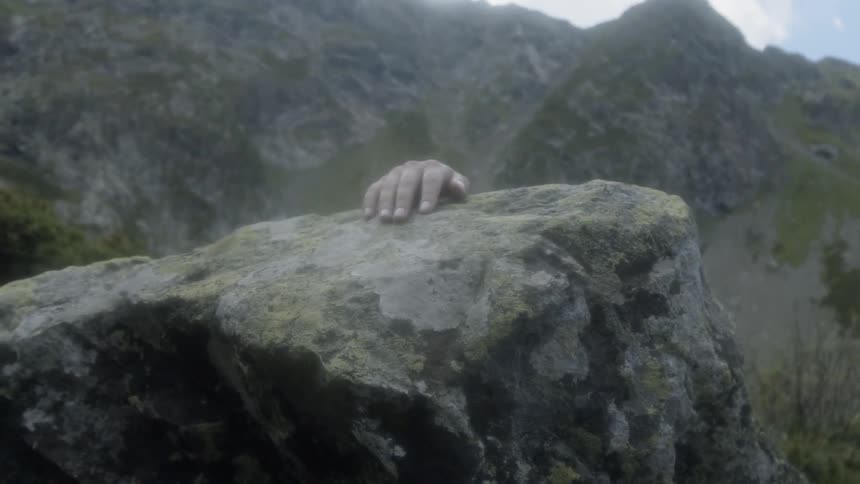 A person's hand on top of a rock on a ridge