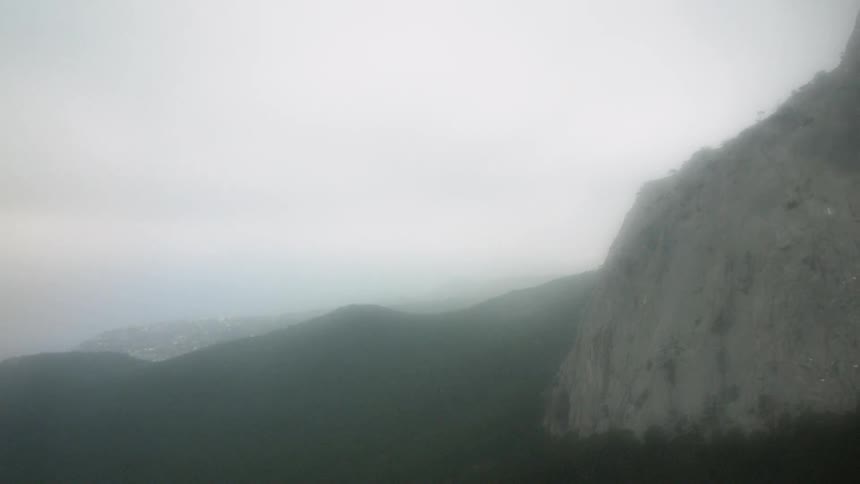 Some green mountains among others on a very cloudy day