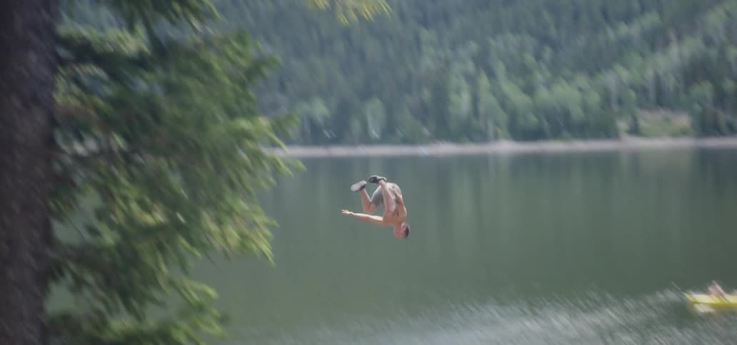A man swings and dives into the water