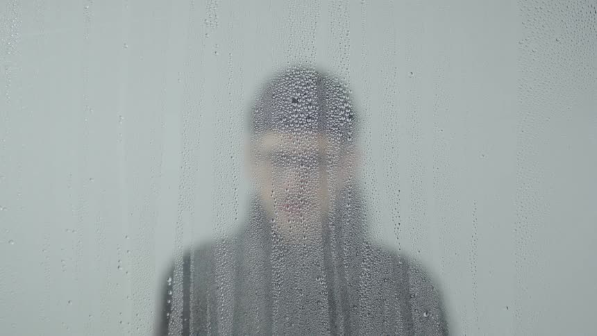 A man walks towards a hazy window