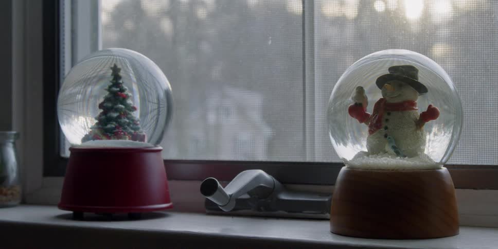 Two snow globes sit on a windowsill