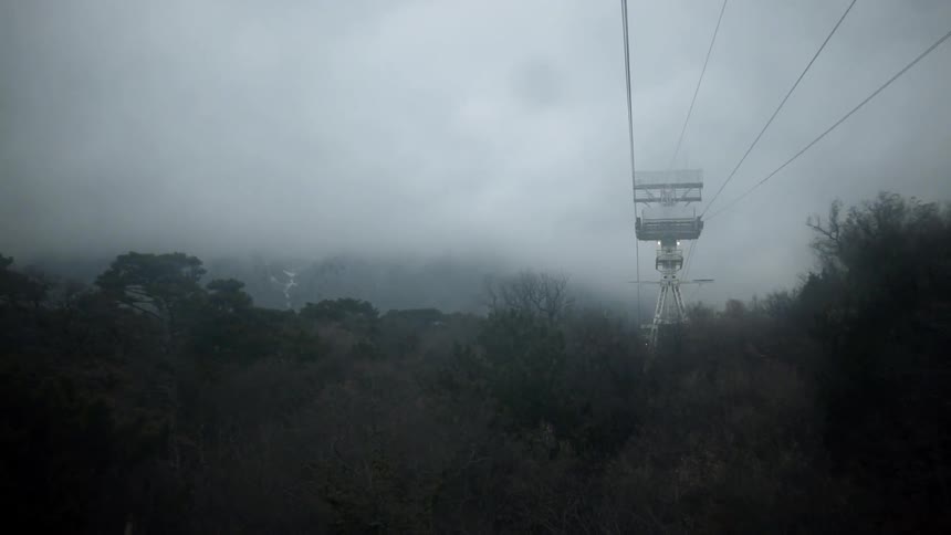 Ski lift wires head up the mountain on a cloudy day