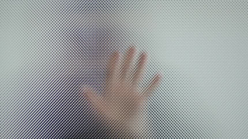 A person wipes their hand on a glass window