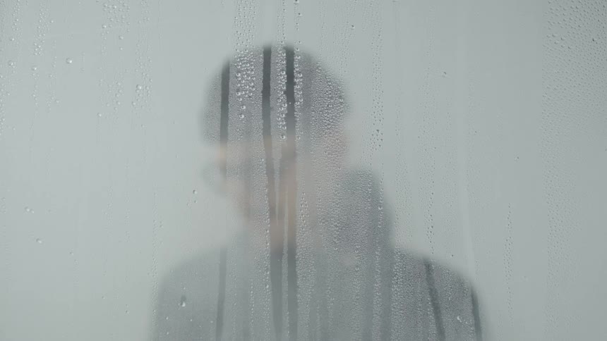 Man wears glasses near a cloudy window