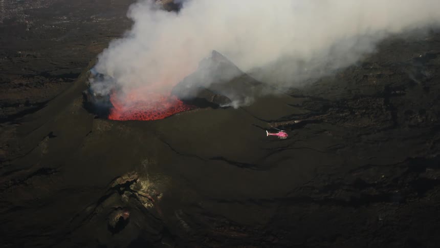 A helicopter flies around an active volcano