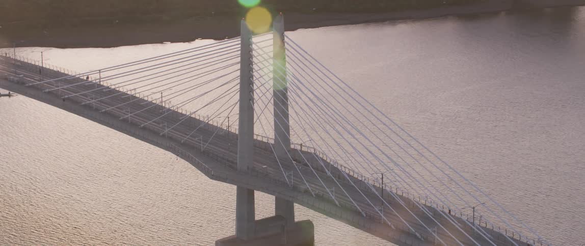 A city bridge spans a river at sunset