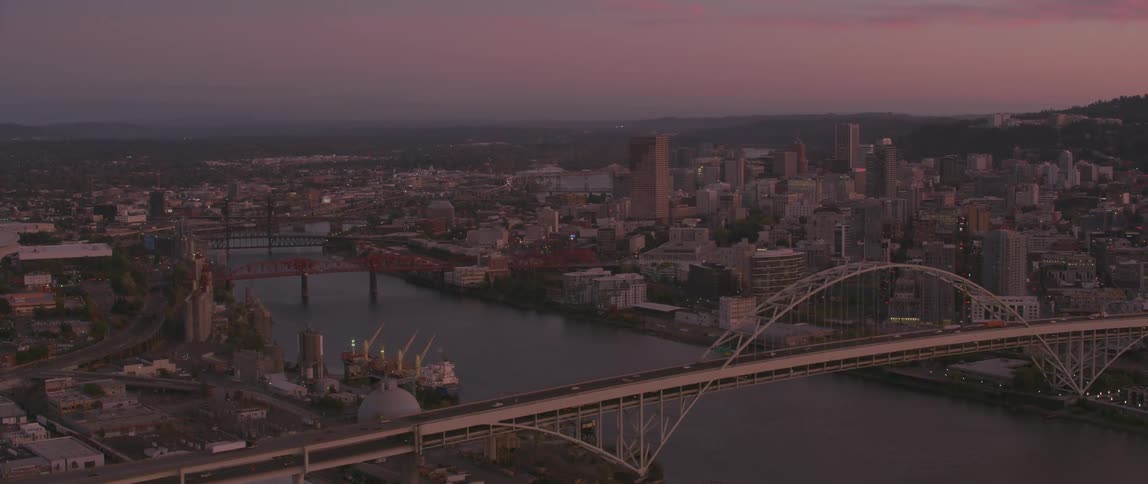 Cars driving over a bridge leading to a city