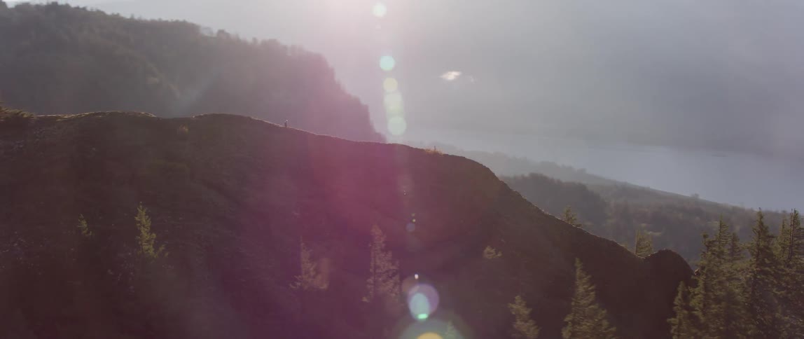 A man is hiking on a steep ridge in the mountains on a sunny day